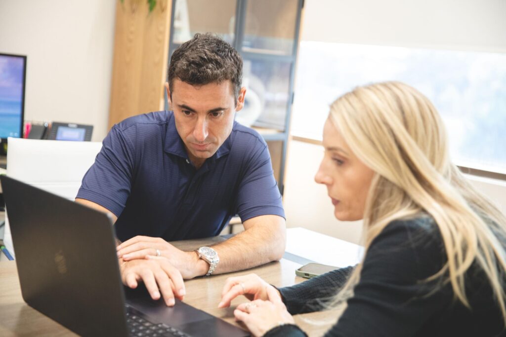 An orthodontic consultant working hands-on with a practice team member during a coaching session focused on implementation and results